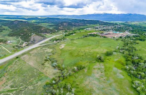 Rural landscape in Mancos, Colorado, with hills, trees, and a highway; ideal for commercial real estate opportunities.